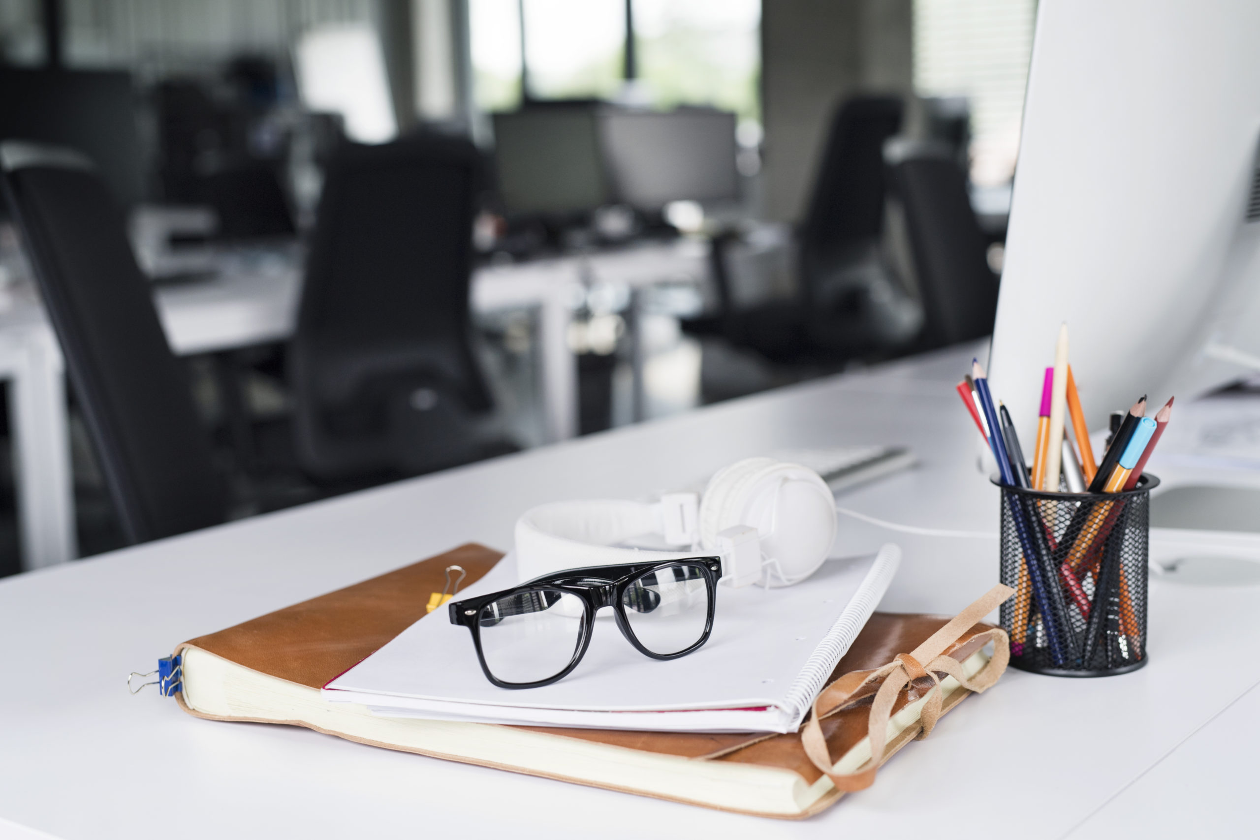 Office desk with computer, notebook and eyeglasses. Zpryme